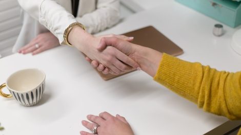 Dos personas estrechando las manos sobre un escritorio.