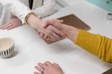 Dos personas estrechando las manos sobre un escritorio.