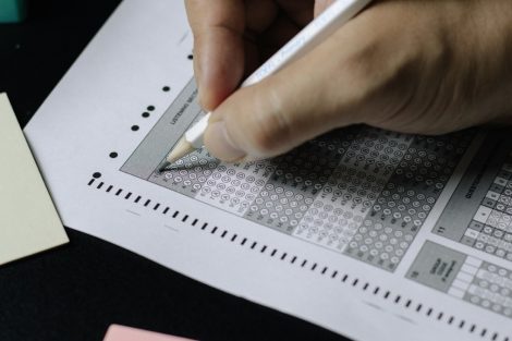 Mano completando una prueba estandarizada de opción múltiple con lápiz.